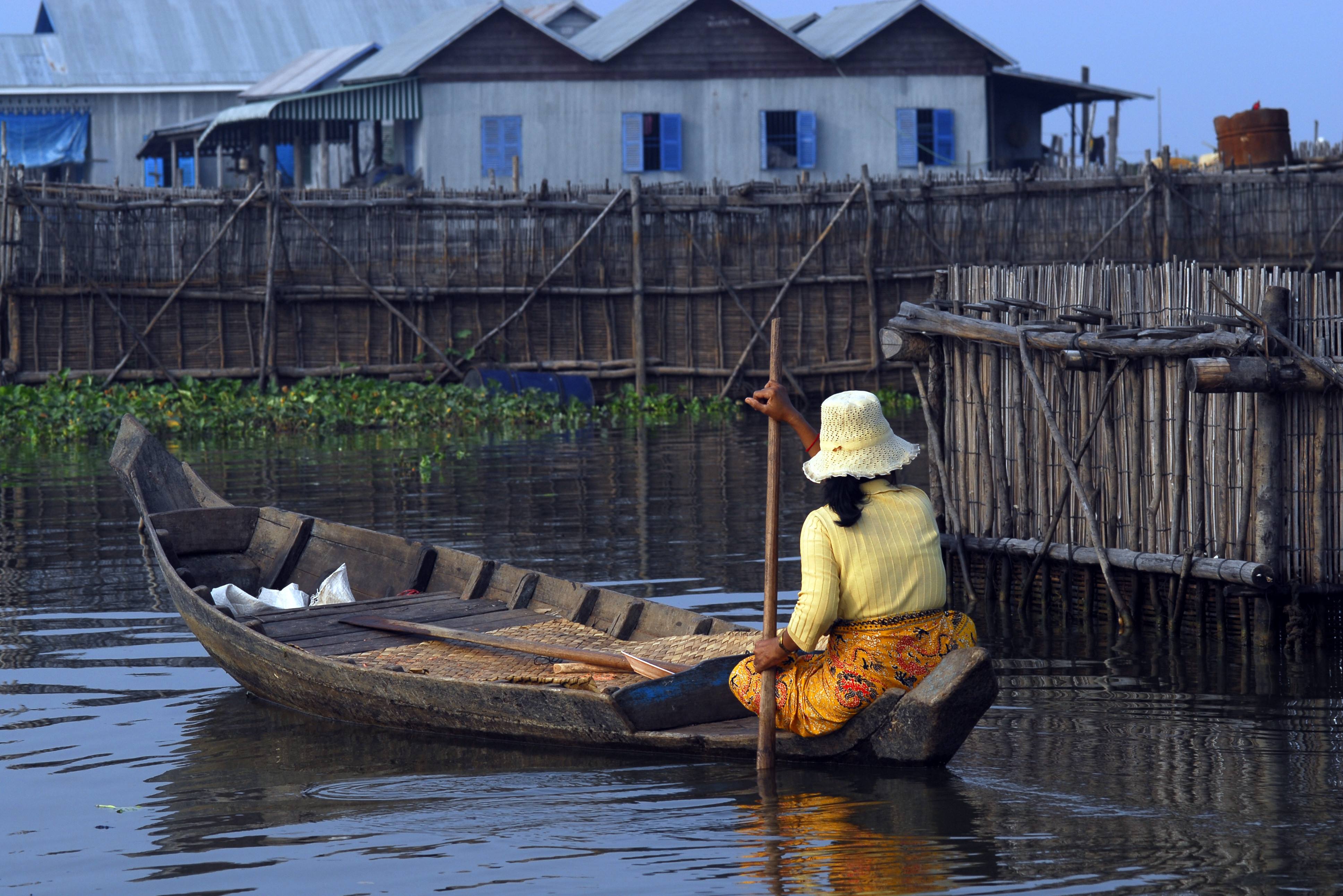 Vrouw vaart door drijvend dorp op het Tonle Sap meer
