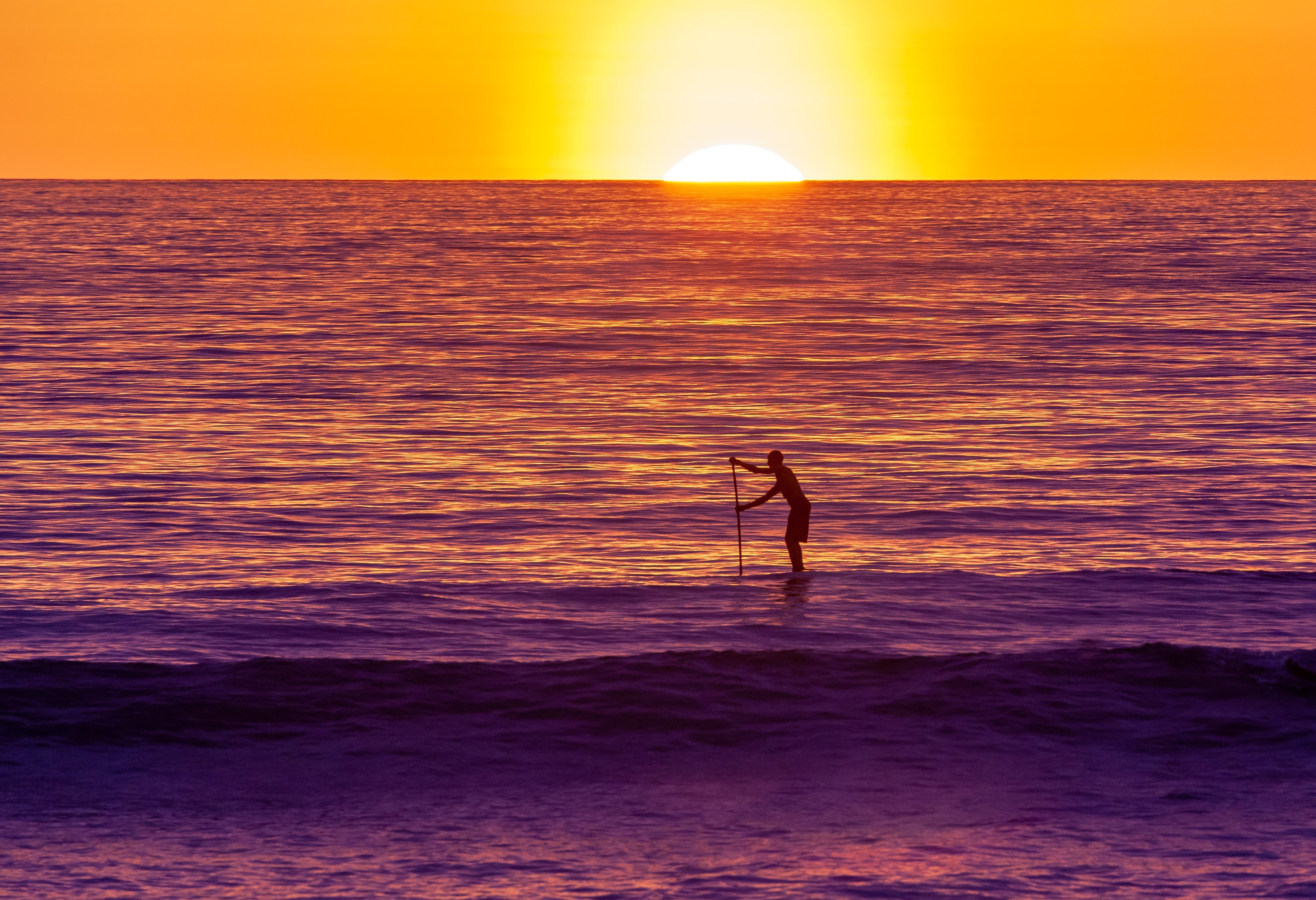 Paddle surfen bij zonsondergang