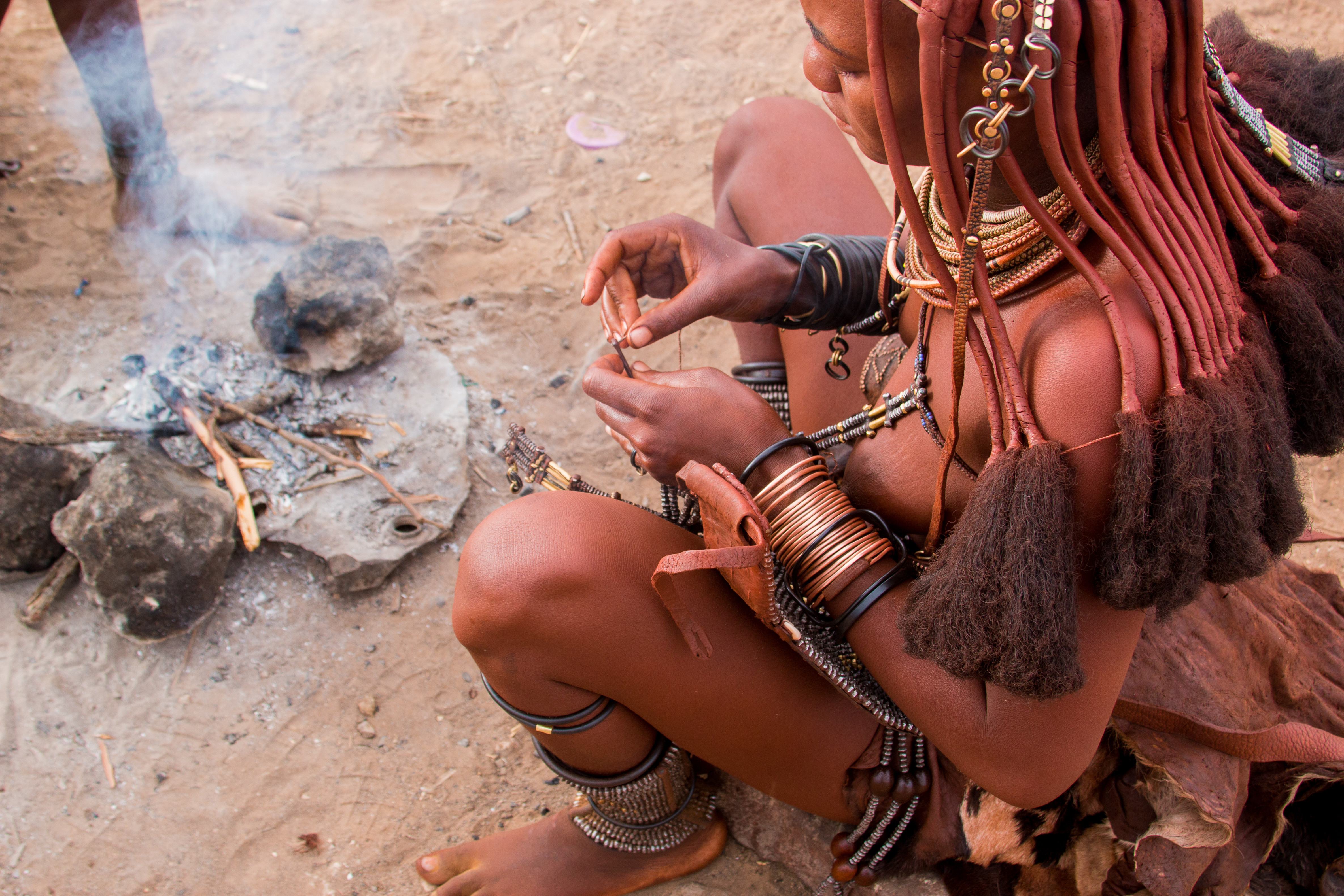 Een himba vrouw aan het koken bij het kampvuur in Namibie