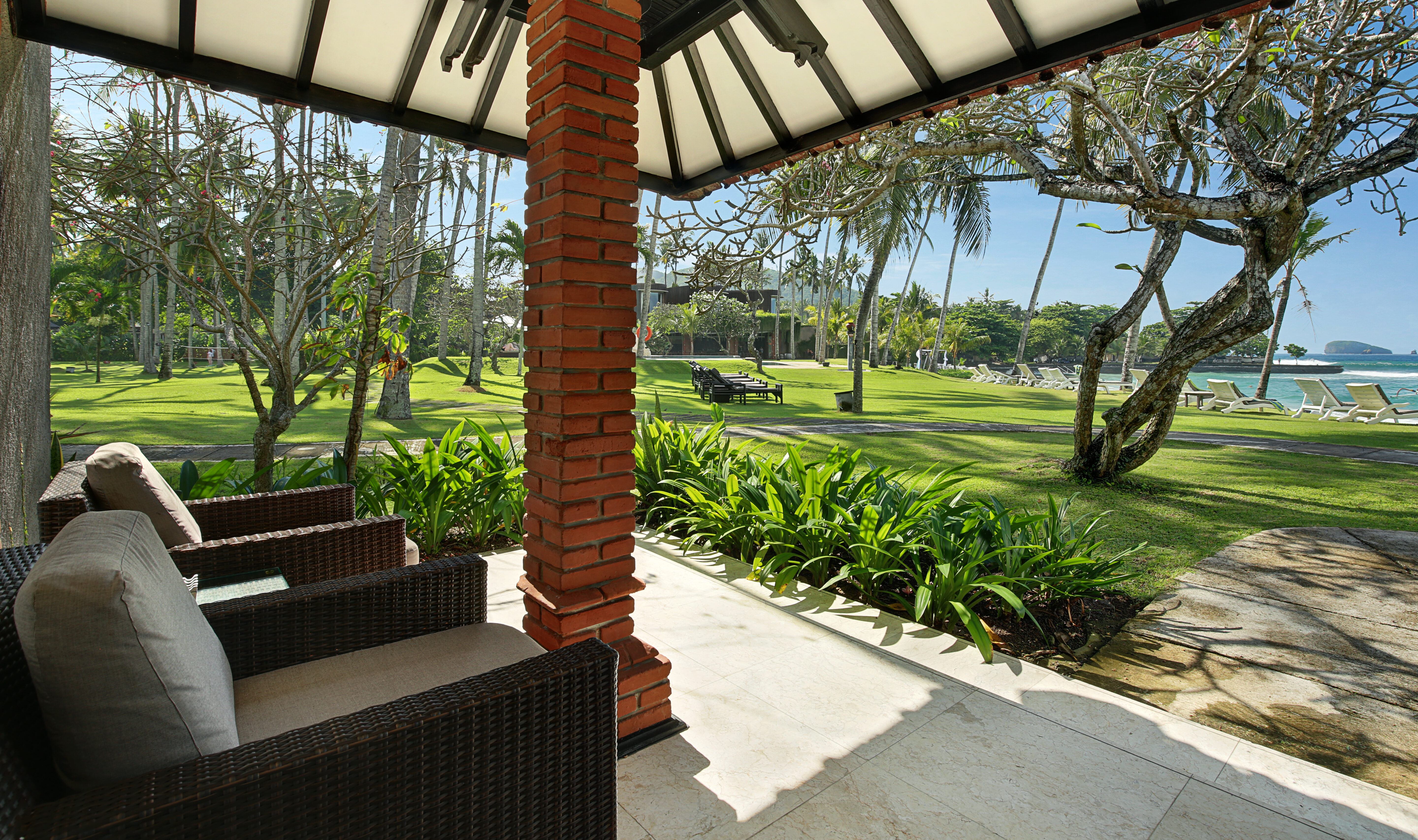 Terras van de Deluxe Ocean Bungalow in het Candi Beach Resort in Candidasa op Bali