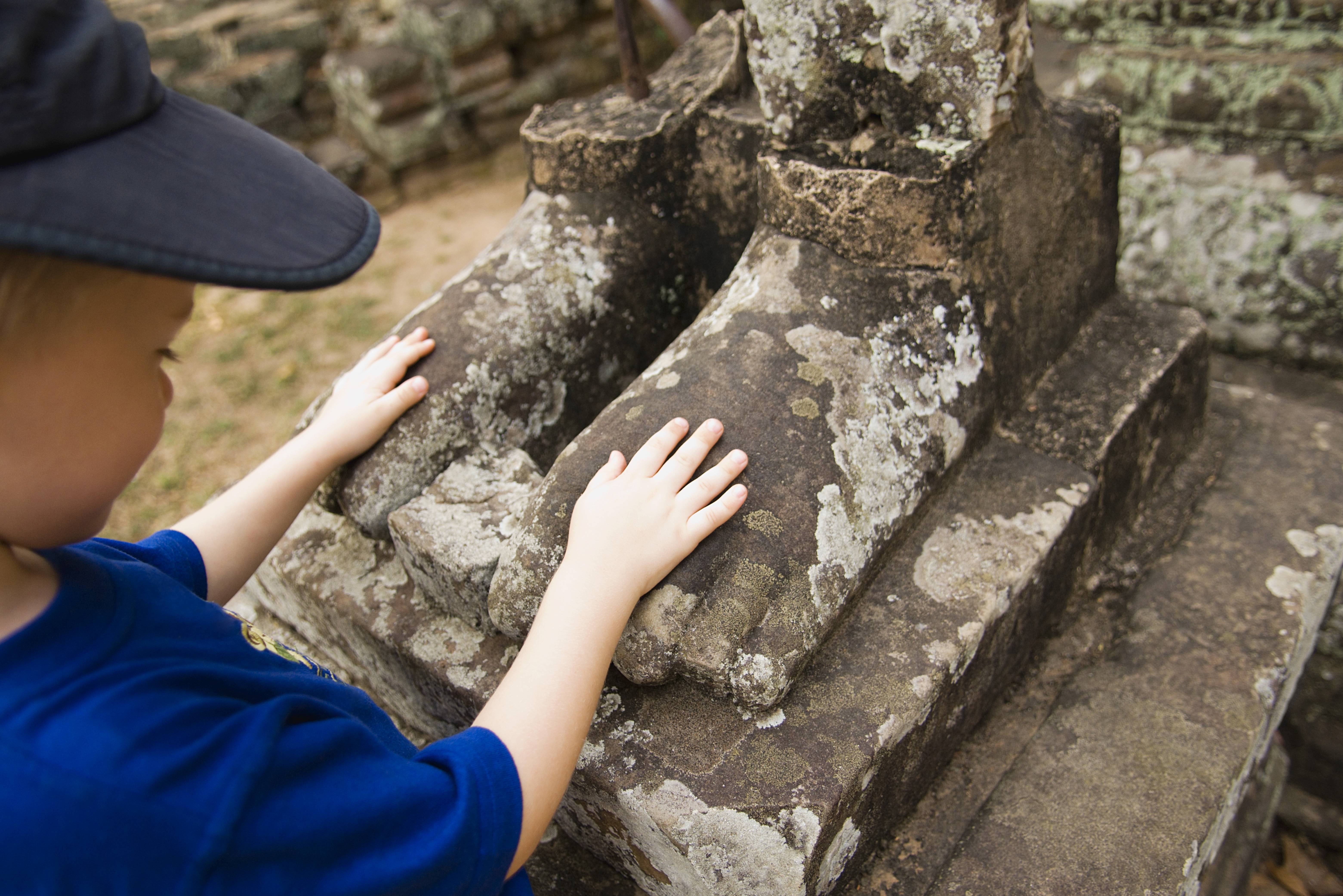 Jongetje bij standbeeld in het Angkor tempelcomplex in Cambodja