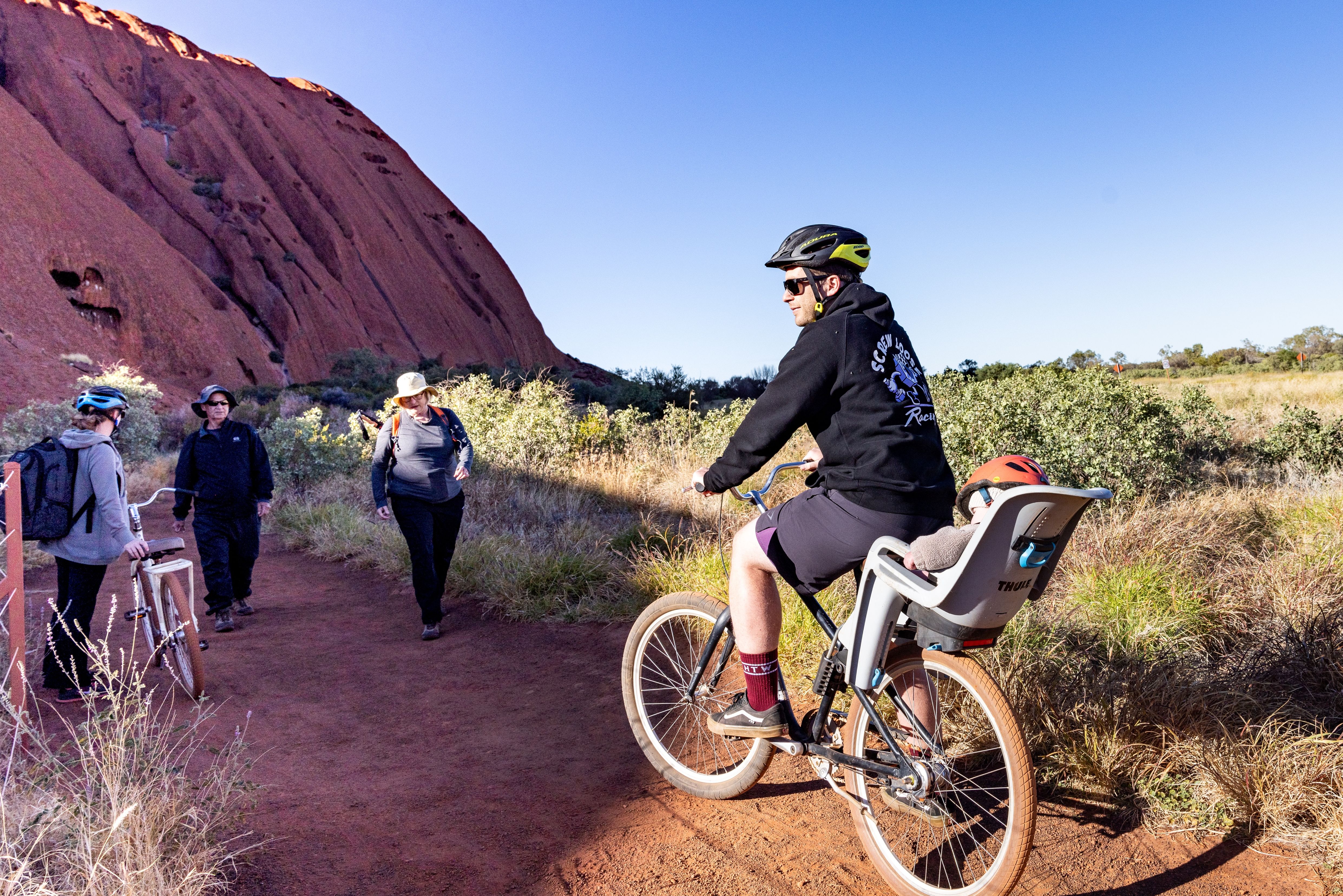 Fietsen met een fietstoeltje achterop voor jonge kinderen bij Uluru in Australie