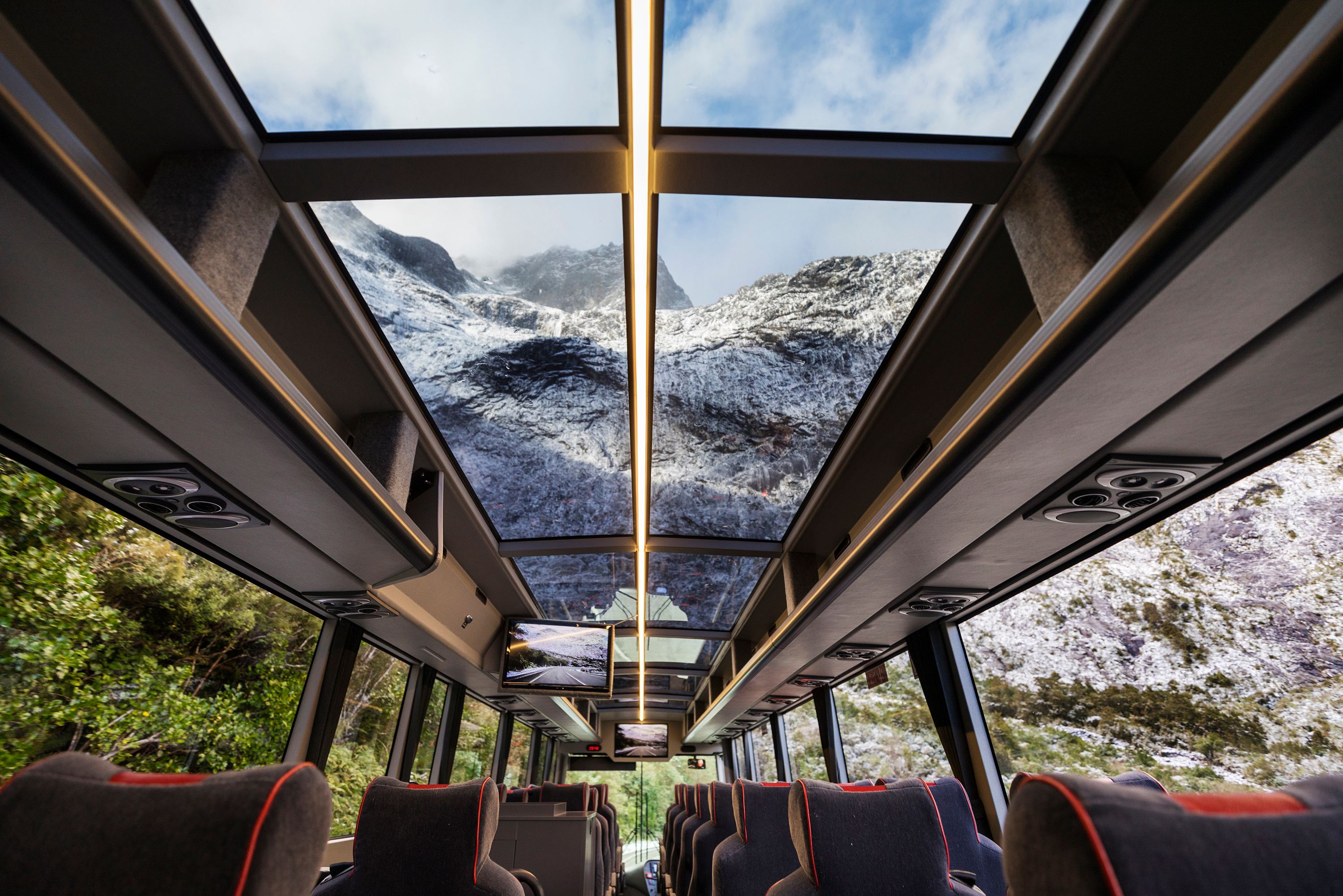 Bus met grote ramen en panormisch dak over de Milford Road naar Milford Sound in Nieuw-Zeeland