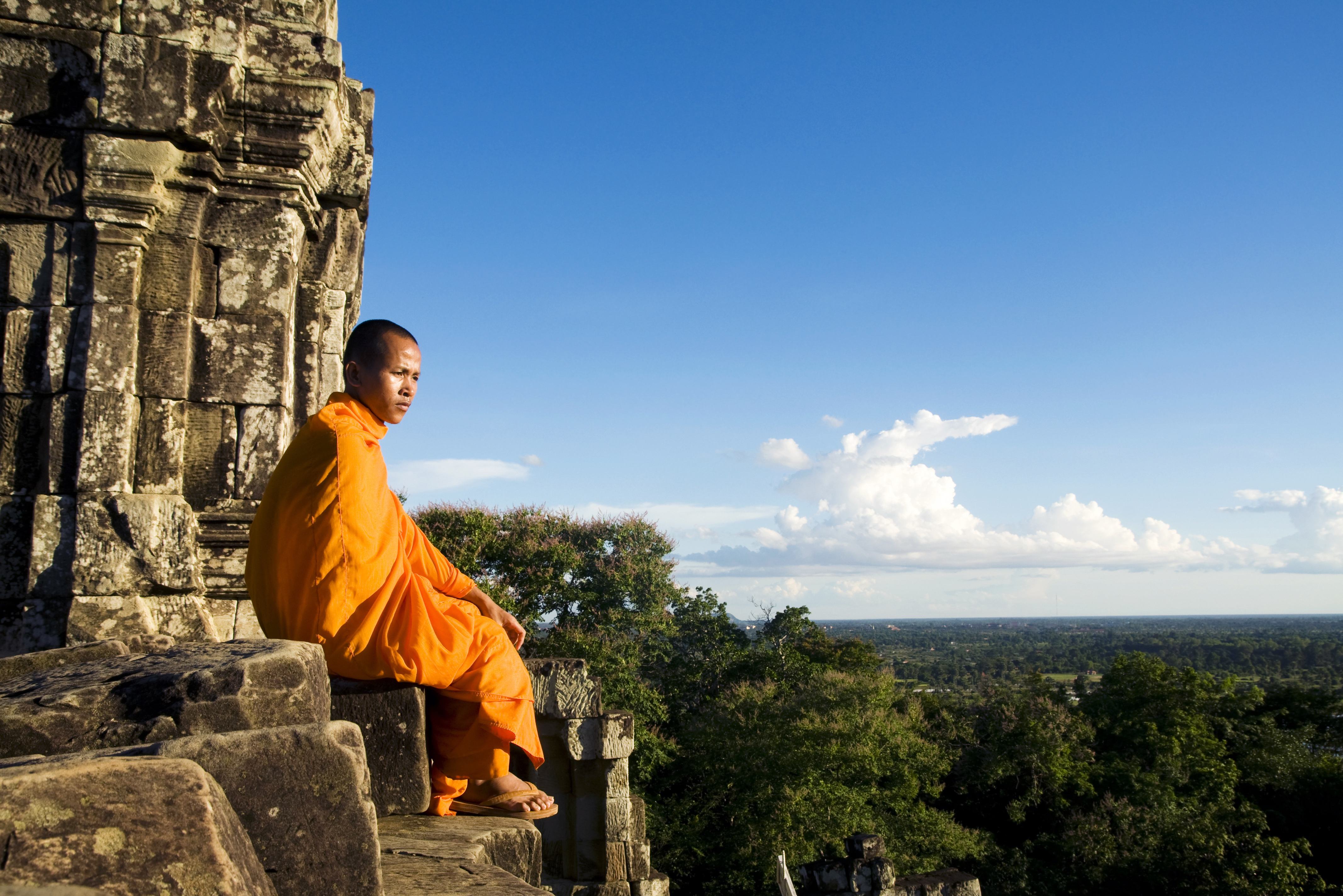 Monnik kijkt uit over het Angkor tempelcomplex in Cambodja