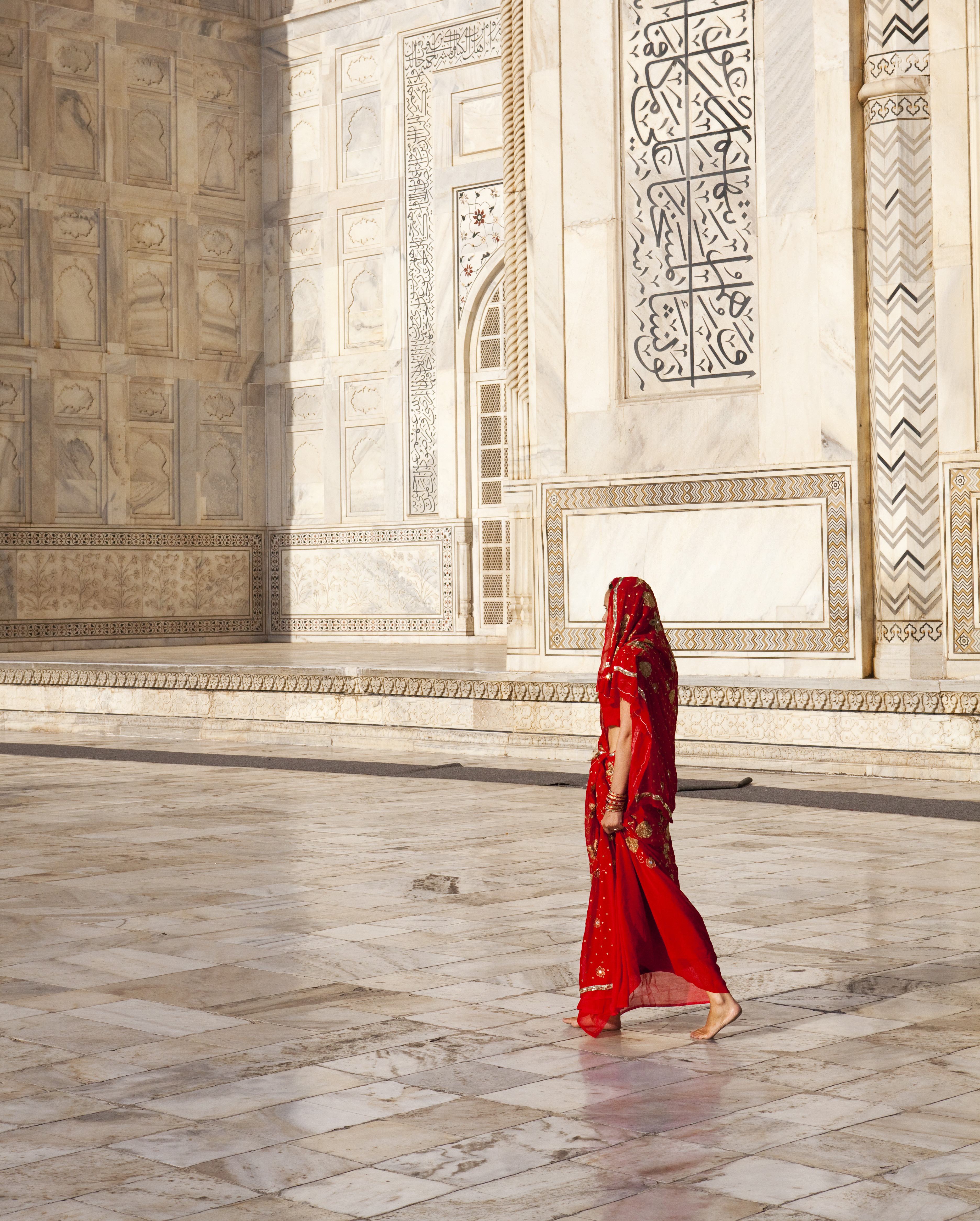 Een vrouw met rode sari bij de Taj Mahal in Agra, India