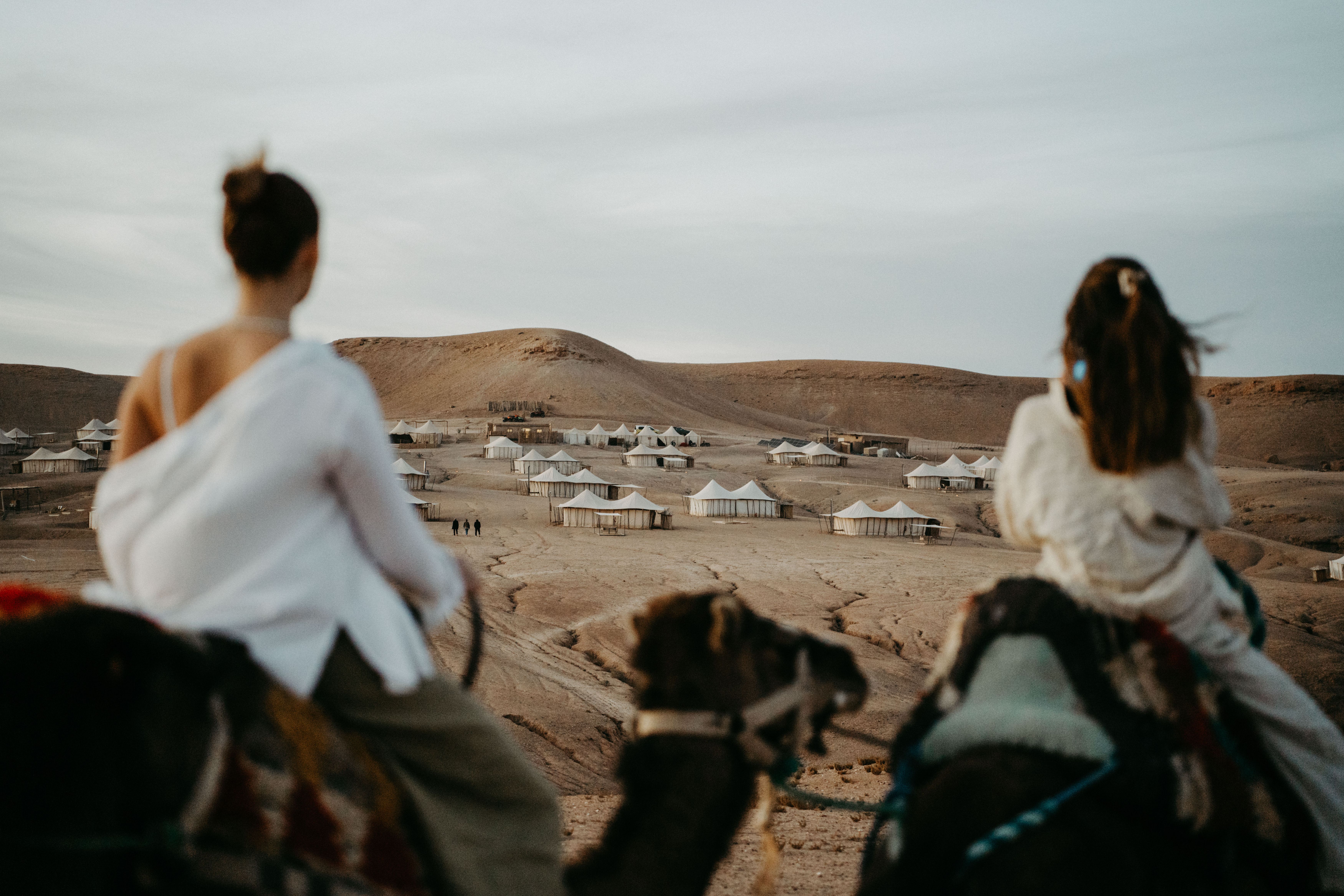 Marokko-Marrakesh-Scarabeo-Camp-The-Stone-Camp-Vrouwen-op-kameel-uitzicht-op-tent